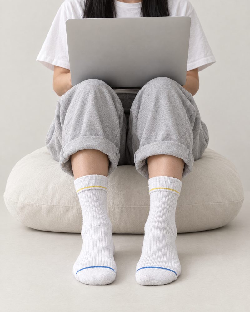 White pair worn while working on a laptop, seated on a floor cushion