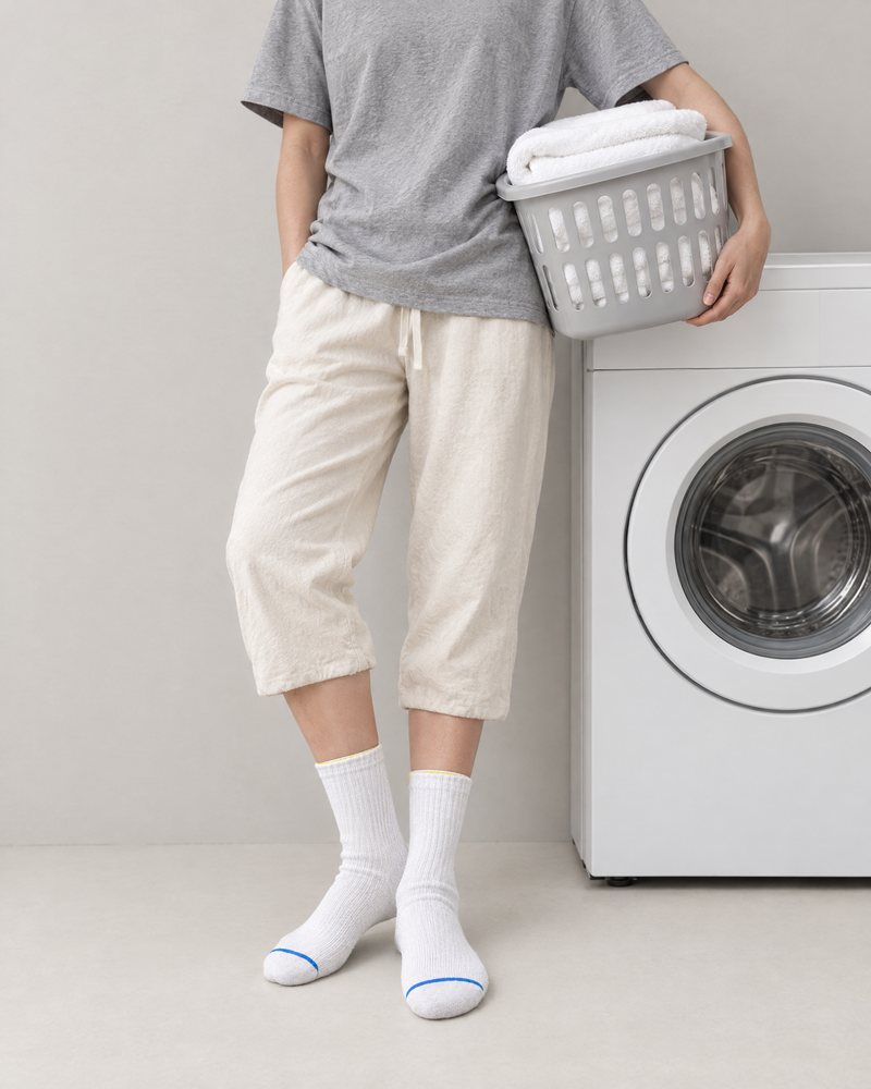White pair worn on laundry day, beside a washing machine with a basket of towels
